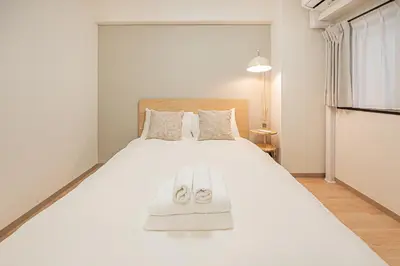a bedroom with a large white bed with slippers on it at Diamond Mansion Apartment Hotel in Tokyo