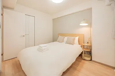 a white bedroom with a large white bed in it at Diamond Mansion Apartment Hotel in Tokyo