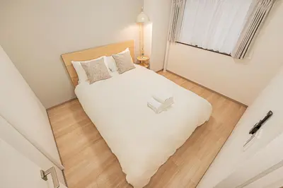 a bedroom with a large white bed and a window at Diamond Mansion Apartment Hotel in Tokyo