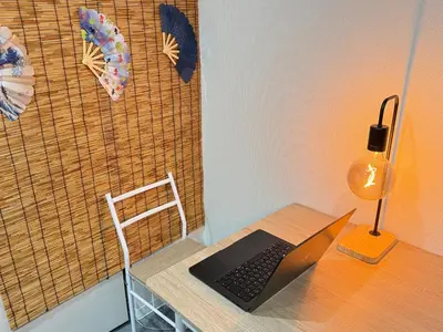 a laptop computer sitting on a desk with a lamp at Wabi Sabi Hostel Shinjuku West in Tokyo