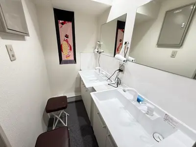 a white bathroom with two sinks and a mirror at Wabi Sabi Hostel Shinjuku West in Tokyo