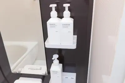a bathroom with three bottles of soap and a mirror at Karabiner House Ikebukuro in Tokyo