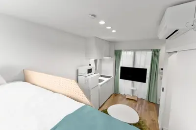 a white bedroom with a bed and a tv at 3\u540d\u5bbf\u6cca \u897f\u65b0\u5bbf\u30a2\u30d1\u30fc\u30c8\u30e1\u30f3\u30c8 in Tokyo