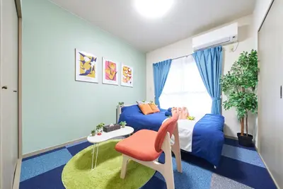 a bedroom with a blue bed and a table and a chair at Shamrock Aoto 302 Cozy Tokyo Stay Near Station Airport Disney Access in Tokyo