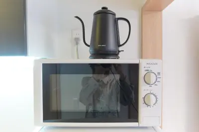 a person taking a picture of a microwave with a tea kettle on top at monthly \u30c9\u30df\u30fc\u30eb\u4e16\u7530\u8c37 in Tokyo
