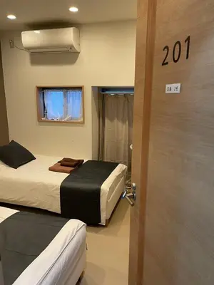 a room with two beds and a door with a window at Shin-Okubo, Shinjuku's best central location, private bathroom and toilet in Tokyo