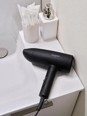 a black hair dryer sitting on a white table at 7C's HOUSE in Tokyo