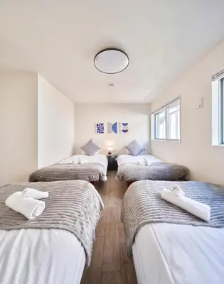 a room with four beds in a row with a mirror at 7C's HOUSE in Tokyo