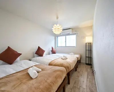 a row of beds in a room with a chandelier at 7C's HOUSE in Tokyo