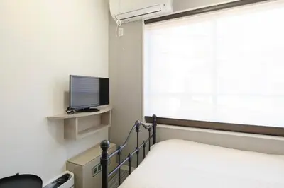 a bedroom with a bed and a television and a window at monthly HJ PLACE TAKANAWA in Tokyo