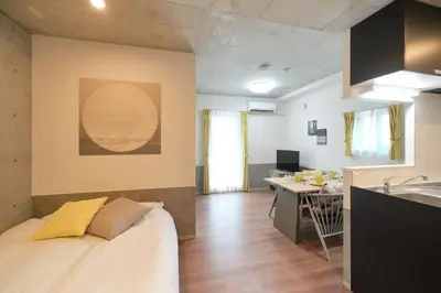 a room with a bed and a kitchen and a desk at monthly J-ARC\u65b0\u5bbf in Tokyo