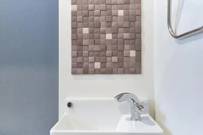 a bathroom with a sink and a painting on the wall at monthly J-ARC\u65b0\u5bbf in Tokyo