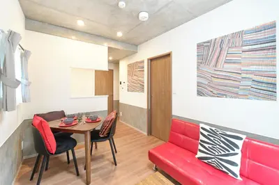 a living room with a red couch and a table at monthly J-ARC\u65b0\u5bbf in Tokyo