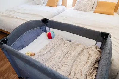 a baby in a crib sitting next to a bed at KOTOBUKI House - Perfect for Groups - 3 Bedrooms, 3 Baths in Tokyo