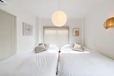 two beds in a room with white walls at KOTOBUKI House - Perfect for Groups - 3 Bedrooms, 3 Baths in Tokyo