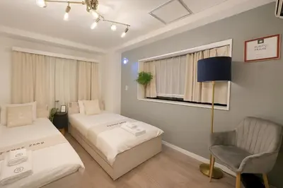 a bedroom with two beds and a chair and a lamp at Panda Stay\u65e9\u7a32\u7530\u99c5,\u65e9\u7a32\u7530\u5927\u5b66\u5f92\u6b691\u5206,\u9ad8\u7530\u99ac\u5834\u30a8\u30ea\u30a2\u8cb8\u5207\u90e8\u5c4b in Tokyo