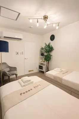 a white room with two beds and a plant at Panda Stay\u65e9\u7a32\u7530\u99c5,\u65e9\u7a32\u7530\u5927\u5b66\u5f92\u6b691\u5206,\u9ad8\u7530\u99ac\u5834\u30a8\u30ea\u30a2\u8cb8\u5207\u90e8\u5c4b in Tokyo