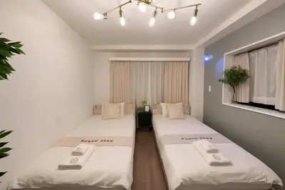 two beds in a room with white walls at Panda Stay\u65e9\u7a32\u7530\u99c5,\u65e9\u7a32\u7530\u5927\u5b66\u5f92\u6b691\u5206,\u9ad8\u7530\u99ac\u5834\u30a8\u30ea\u30a2\u8cb8\u5207\u90e8\u5c4b in Tokyo