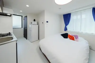 a small white room with a bed and a kitchen at L