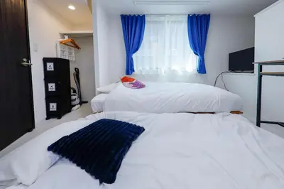 two beds in a bedroom with blue curtains at L