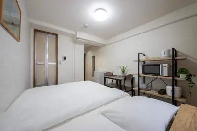 a bedroom with two white beds and a tv at CraftFlat Numabukuro 306, uphill residence in Tokyo