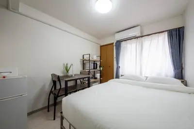 a bedroom with a bed and a desk and a window at CraftFlat Numabukuro 306, uphill residence in Tokyo