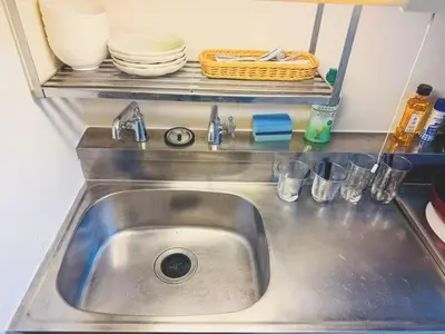 a sink in a kitchen with dishes on a shelf at Shinjuku Downtown\u65b0\u5bbf in Tokyo