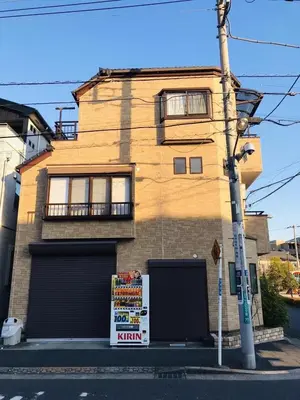 a brown brick building with two garage doors on a street at \u4e00\u53f6\u8ed2 \u6771\u4eac\u6c11\u5bbf One-Leaf House in Tokyo