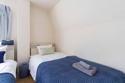a bedroom with a bed with a blue blanket at \u30a2\u30f3\u30c9\u30b9\u30c6\u30a4\u6c38\u798f3\u4e01\u76ee202 in Tokyo