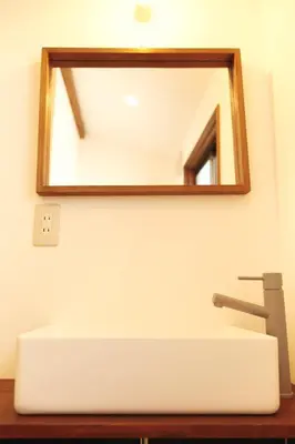 a mirror above a white sink in a bathroom at North Shinjuku House in Tokyo