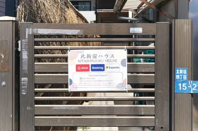 a sign on a gate in front of a building at North Shinjuku House in Tokyo