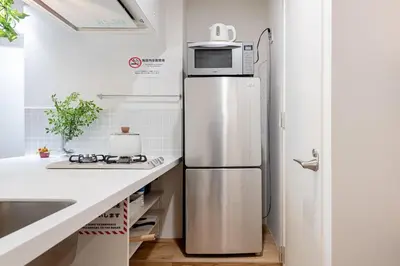 a refrigerator with a microwave on top of it in a kitchen at trias815 \u5e73\u548c\u5cf6201\u53f7\u5ba4 in Tokyo