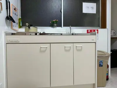 a white kitchen with a sink and a window at \u53cc\u9b5a\u306e\u5bbf\u6c60\u888b in Tokyo
