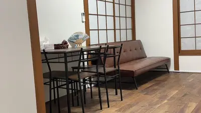 a living room with a couch and a table and chairs at \u53cc\u9b5a\u306e\u5bbf\u6c60\u888b in Tokyo