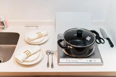 a black pot on a stove with plates and utensils at A1 Shibuya , 1 room, 7 mins to ST Max 2P \u6e0b\u8c37\u5168\u65b0\u88c5\u4fee \u4ea4\u901a\u4e2d\u5fc3 \u8f66\u7ad97\u5206\u949f \u6700\u59272\u4eba \u76f4\u8fbe\u65b0\u5bbf \u6d89\u8c37 \u8868\u53c2\u9053 \u54c1\u5ddd \u6c60\u888b \u4e0a\u91ce \u4ee3\u4ee3\u6728 \u94f6\u5ea7 \u539f\u5bbf in Tokyo