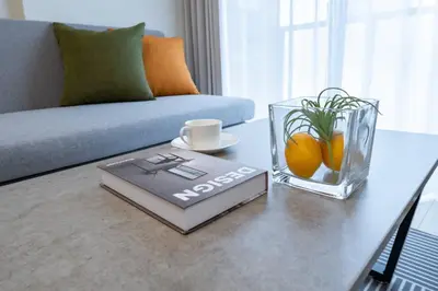 a table with a book and a vase with oranges on it at Daffitto\u62bc\u4e0aII in Tokyo
