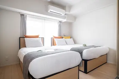 two beds in a room with a window at Daffitto\u62bc\u4e0aII in Tokyo