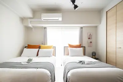 two beds in a room with a window at Daffitto\u62bc\u4e0aII in Tokyo