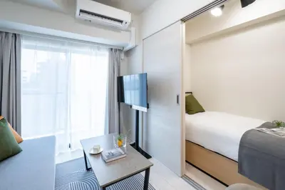 a small hotel room with a bed and a tv at Daffitto\u62bc\u4e0aII in Tokyo