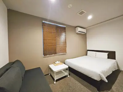 a small bedroom with a bed and a couch at Hermitage Hotel Nishishin in Tokyo