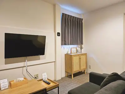 a living room with a couch and a flat screen tv at Hermitage Hotel Nishishin in Tokyo