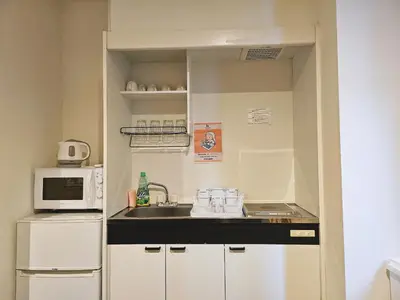 a small kitchen with a sink and a microwave at Hermitage Hotel Nishishin in Tokyo