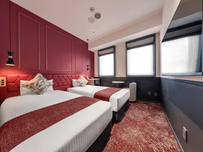 two beds in a room with red walls and windows at Villa Fontaine Tokyo Hibiya in Tokyo