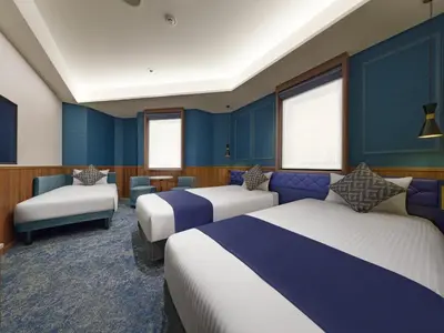 a hotel room with three beds and blue walls at Villa Fontaine Tokyo Hibiya in Tokyo
