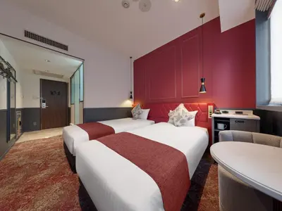 two beds in a hotel room with red walls at Villa Fontaine Tokyo Hibiya in Tokyo