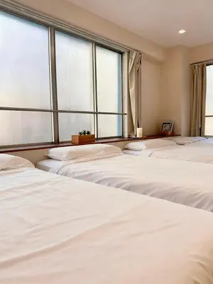 a room with four white beds and large windows at Ikeda Ueno 201 Quad Room in Tokyo