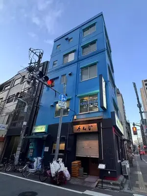 a blue building on a city street with a traffic light at Ikeda Ueno 201 Quad Room in Tokyo