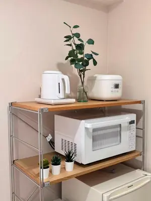 a kitchen shelf with a microwave and other appliances at Ikeda Ueno 201 Quad Room in Tokyo