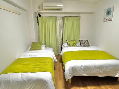 two beds in a room with green curtains at 5min to\u65b0\u5bbfShinjuku in Tokyo