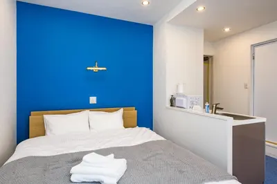 a blue accent wall in a bedroom with a bed at ViLLA SAKURA \u6771\u4eac\u76ee\u9ed2 in Tokyo